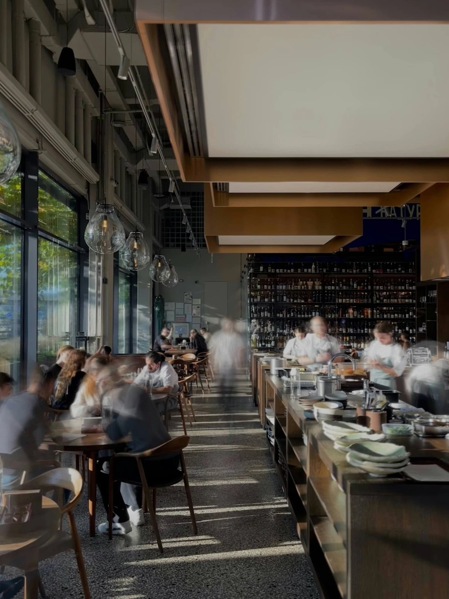 A sunlit open kitchen and dining room during service